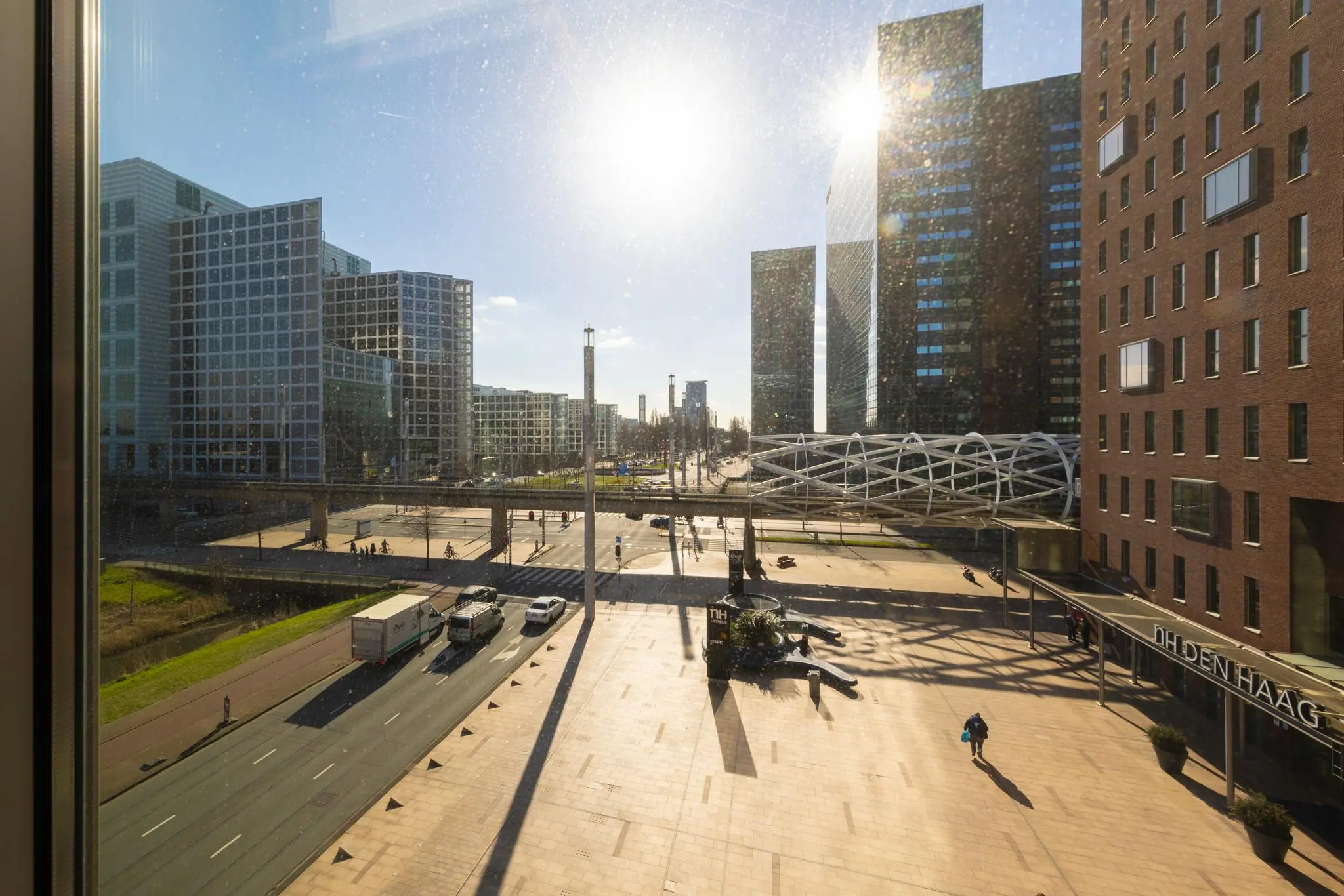 Uitzicht op de Prinses Beatrixlaan in Den Haag met moderne kantoorgebouwen, zonlicht en het NH Hotel op de voorgrond.